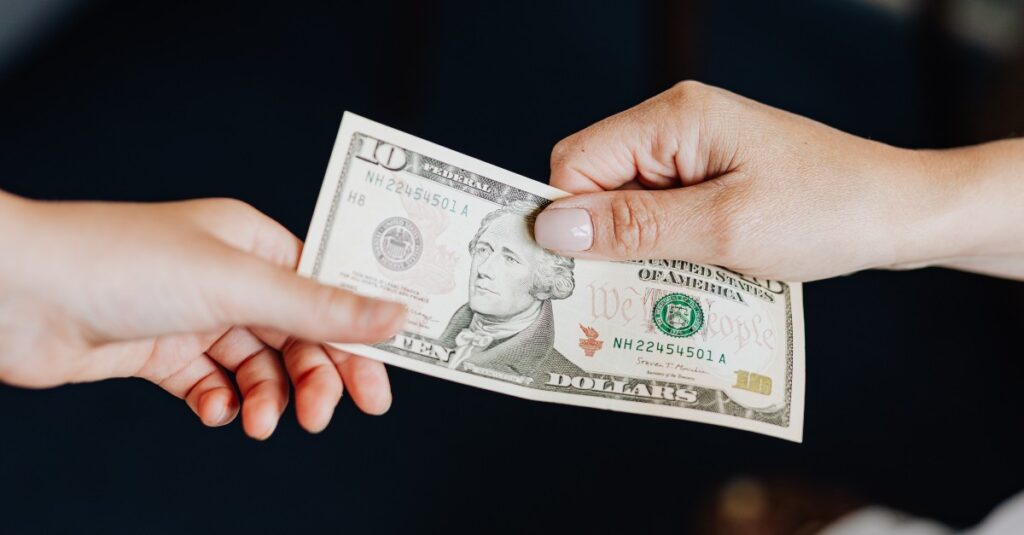 Two hand exchanging a $10 bill