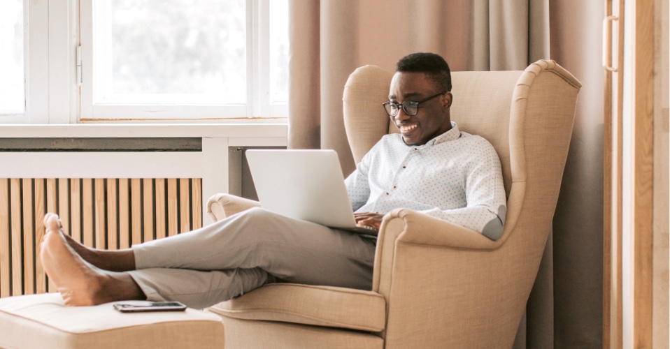 Person working on a laptop in an arm chair with their feet up