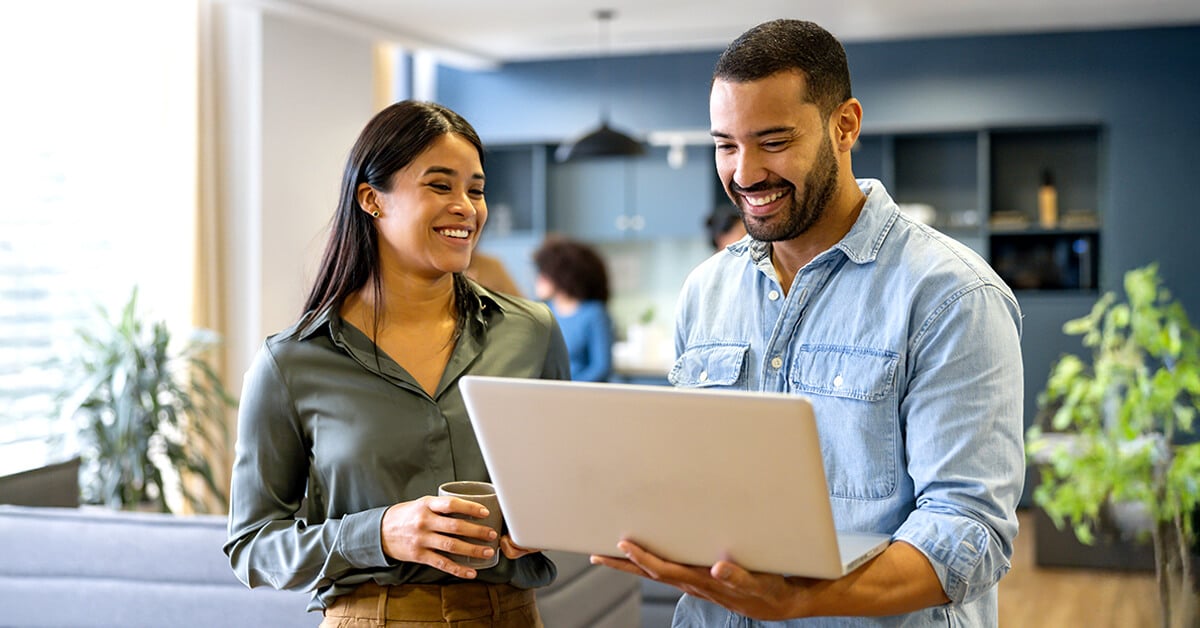 two coworkers looking at computer together and smiling